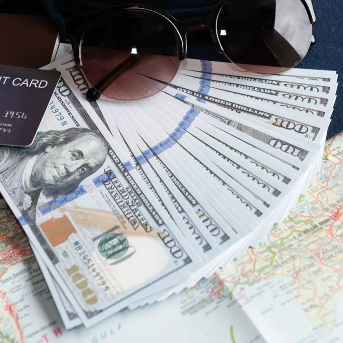 a fan of foerign currency dollar and a sunglass and card on table