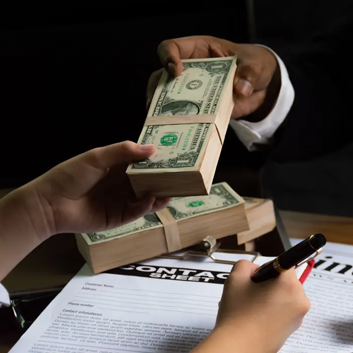 a person handing over a stack of foreign currency