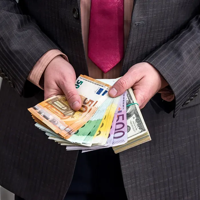 a man in suit holding foreign currencies dollar and euro