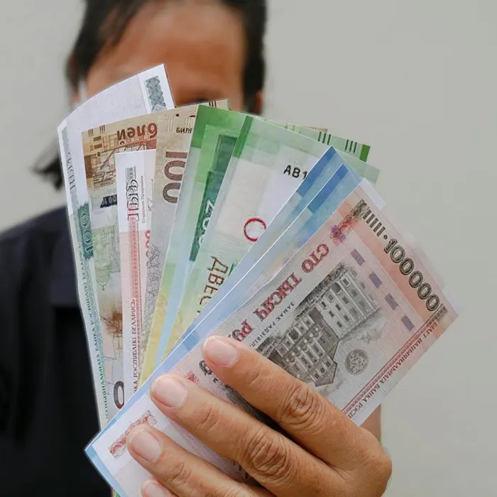 a hand holding different foreign currencies