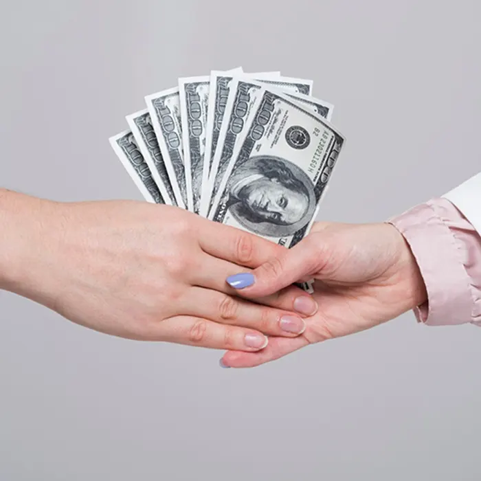 a lady handing over foreign currency dollar to another lady