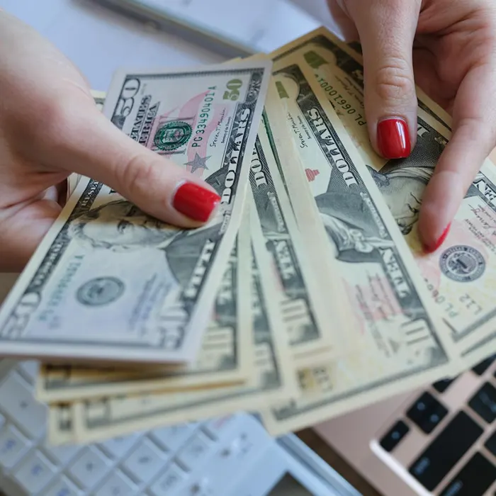 a lady holding foreign currency dollar over the laptop